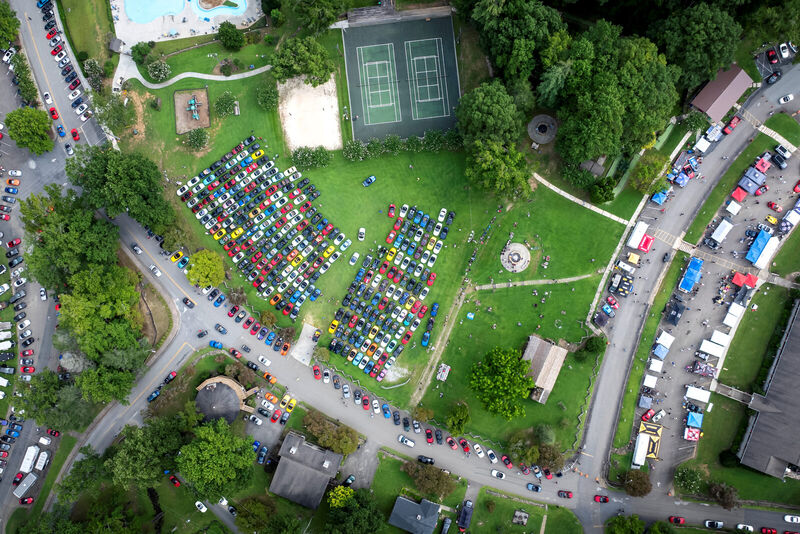 Aerial view of the Miatas at the Gap event site, with rows of parked cars, tents and a tennis court.