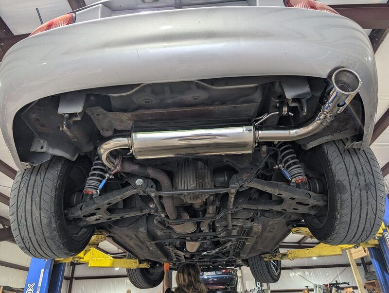 The underside of the Miata on a lift, showing the RoadsterSport 4 muffler from Good-Win Racing.